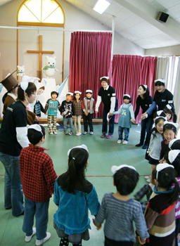 手をつないで輪なる園児と学生たち